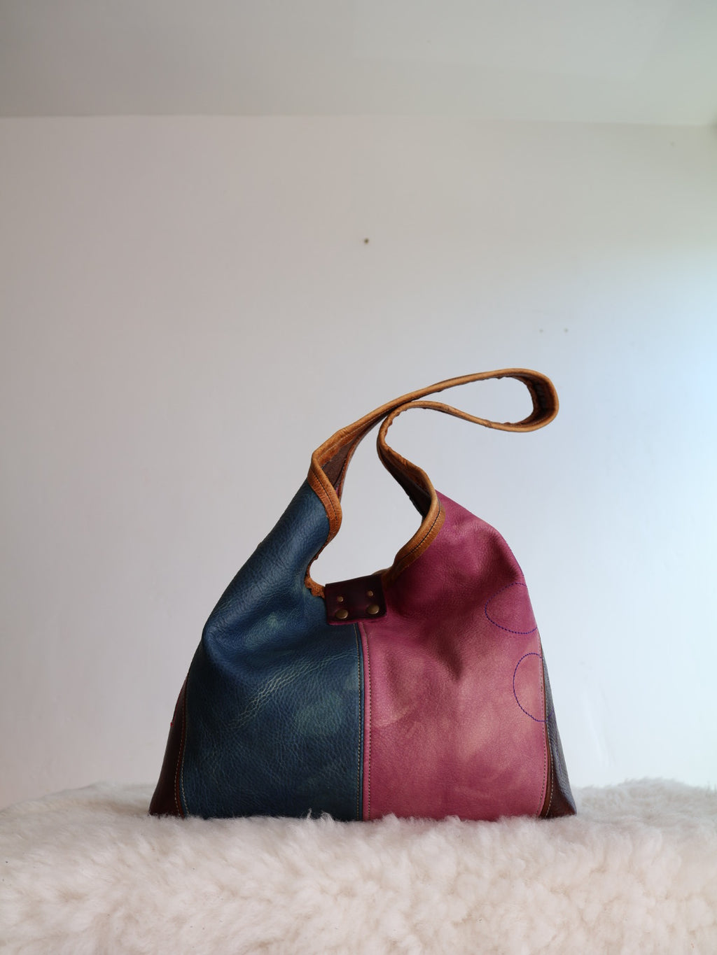Two-tone leather handbag with dark blue and pink colors on a white background.